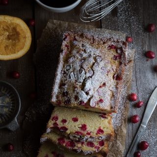 Overhead on the delicious Homemade Cranberry Orange Bread with lots of cranberries around on the table