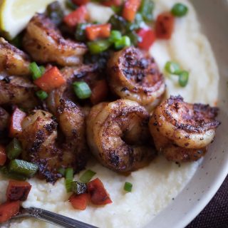 Closeup on the Homemade Cajun Shrimp and Grits served with mashed potatoes and a piece of lemon on top