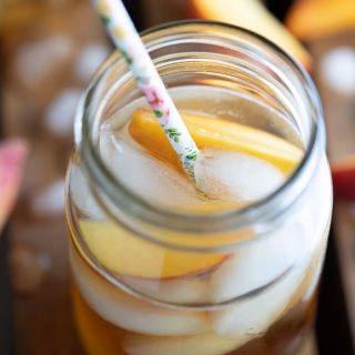 Georgia Peach Cocktail in glass with fruit ice and straw on wooden table top