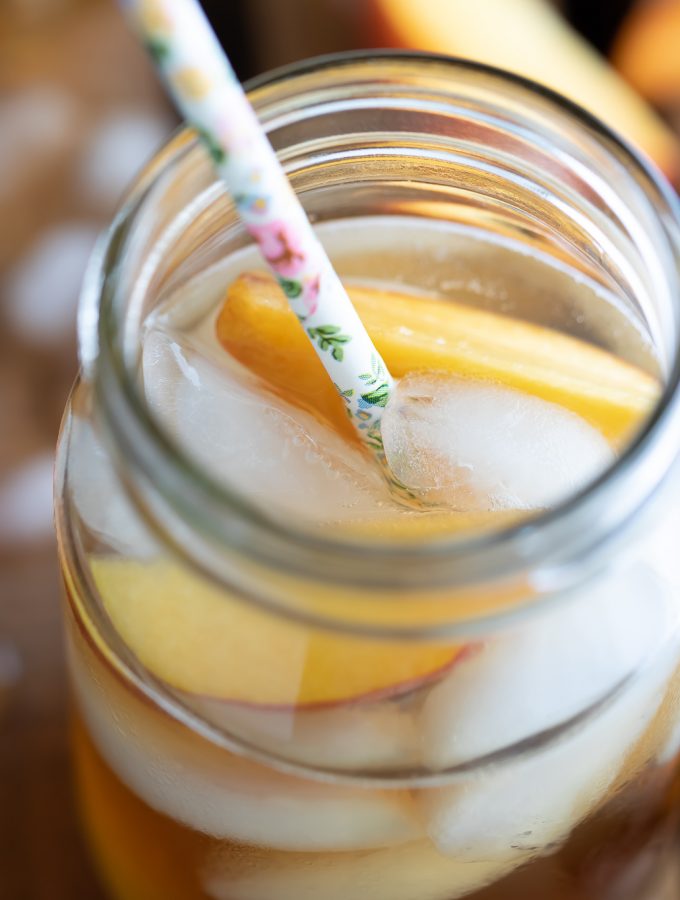 Georgia Peach Cocktail in glass with fruit ice and straw on wooden table top