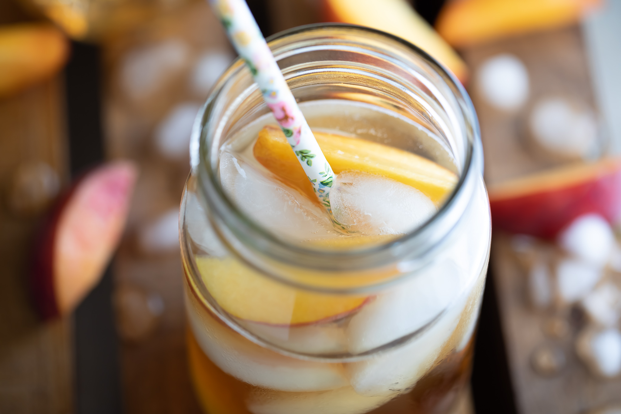 Georgia Peach Cocktail in glass with fruit ice and straw on wooden table top