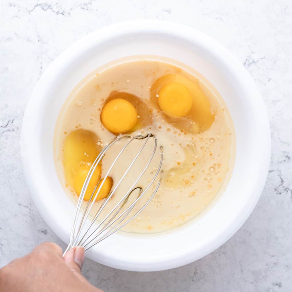 Adding eggs, milk, cooking oil, almond extract, and vanilla extract to the cake mix