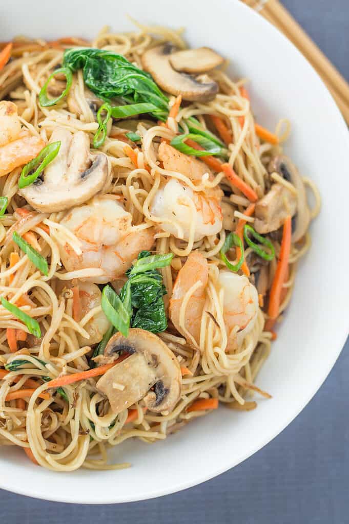 Closeup of the Stir Fried Chinese Noodles with Shrimp in a white bowl with chopsticks on the side