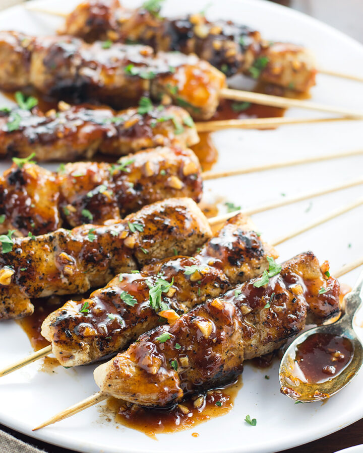 Apricot and Ginger Glazed Chicken Skewers on plate with spoon.