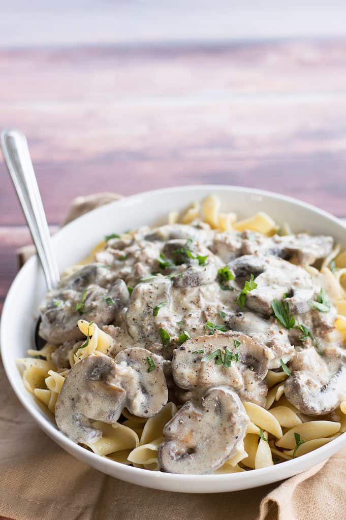 Amazingly Easy Ground Beef Stroganoff made extra special and served on a table covered with a light cloth