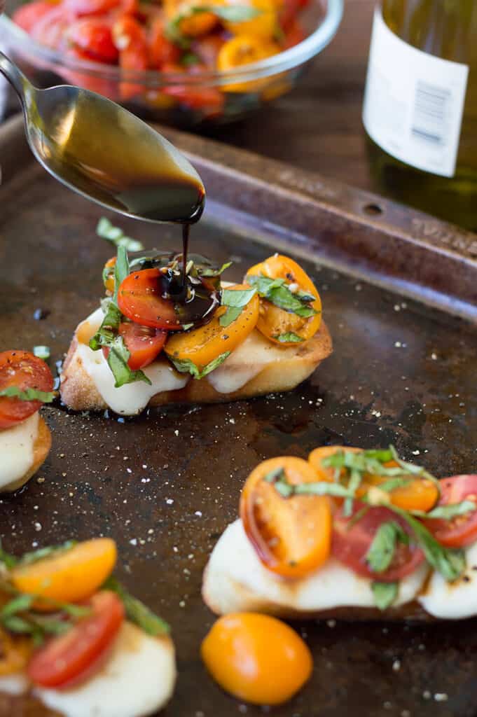 Drizzling sauce on top of each Bruschetta with Cheese served on a metal tray