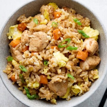 Fried rice with chicken and vegetables in gray bowl with chop sticks.