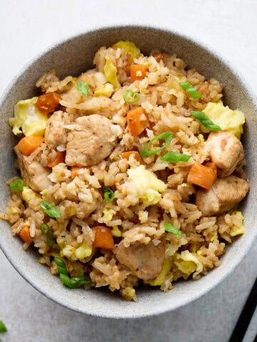 Fried rice with chicken and vegetables in gray bowl with chop sticks.
