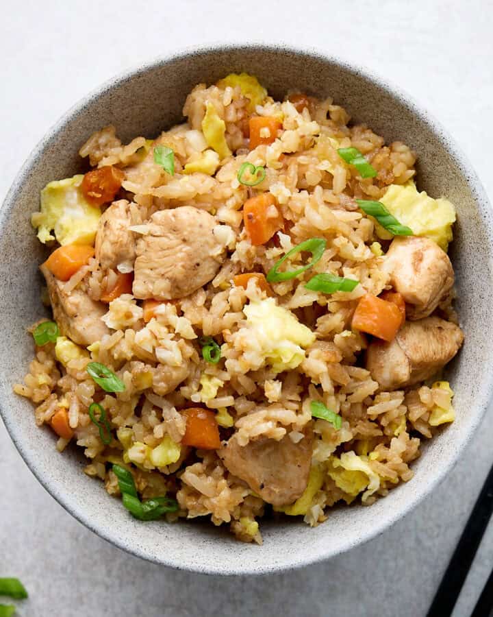 Fried rice with chicken and vegetables in gray bowl with chop sticks.