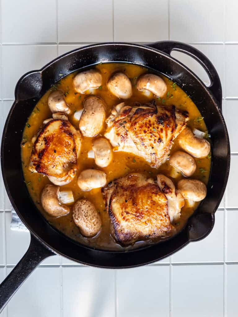 chicken thighs, sauce, mushrooms in pan