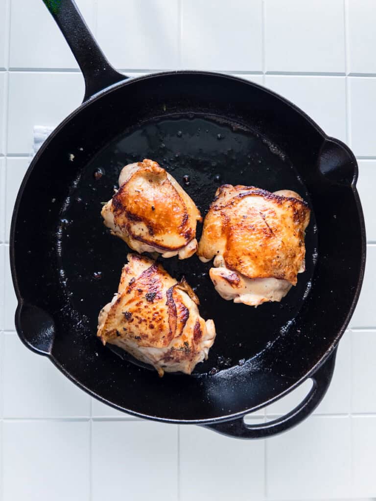 Browned chicken thighs in pan