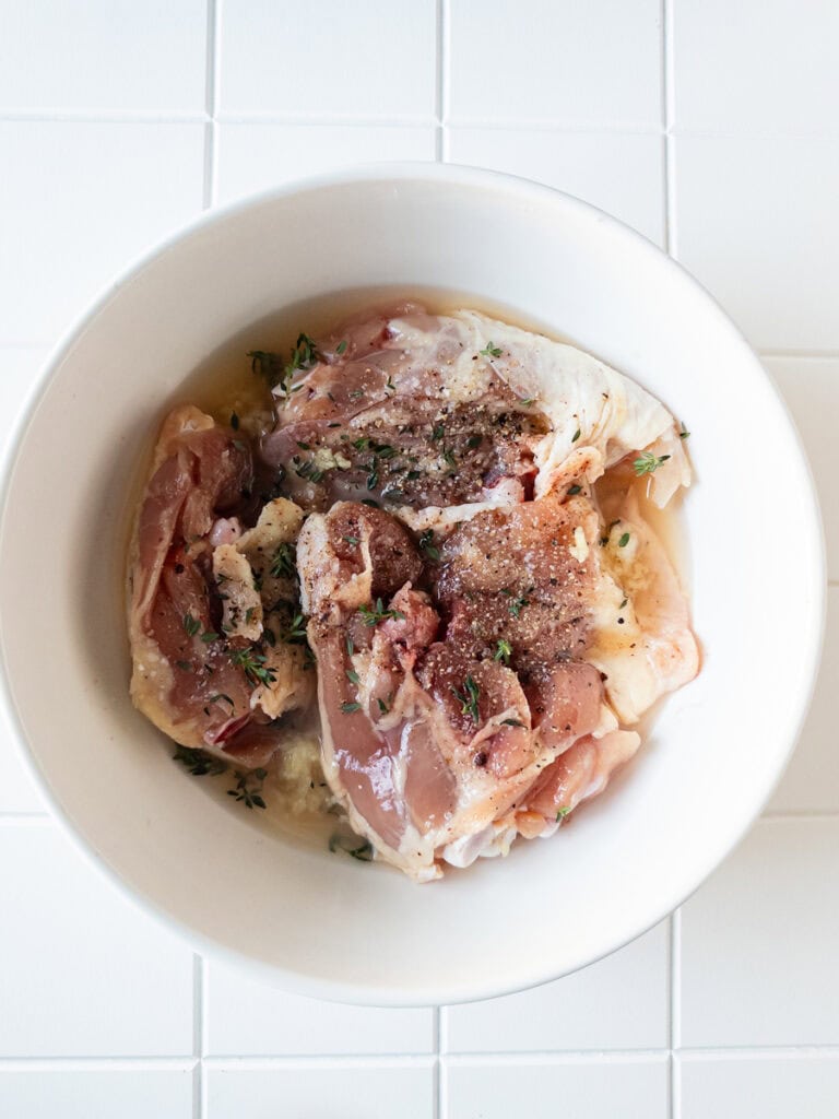 Chicken and marinade in white bowl