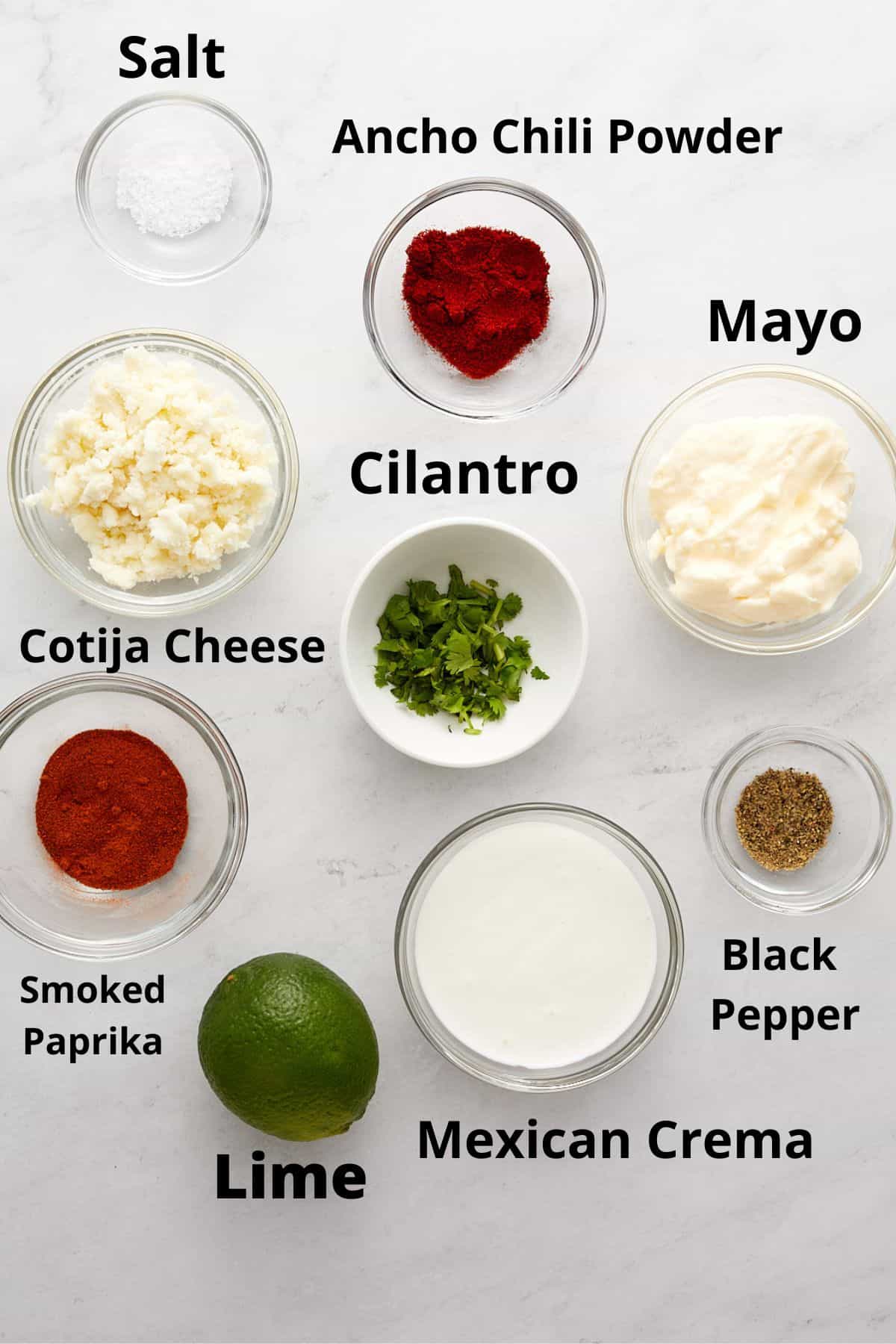 Recipe ingredients in glass and white bowls on white tabletop.