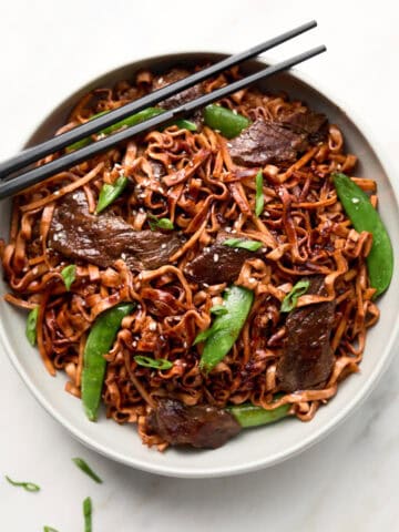 Red Thai Curry Beef Noodle stir fry in white bowl with chopsticks