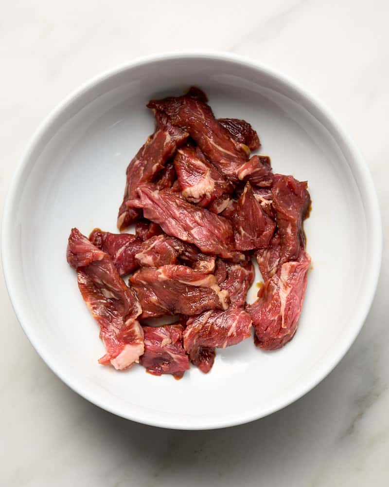 Marinated sliced beef in white bowl. 