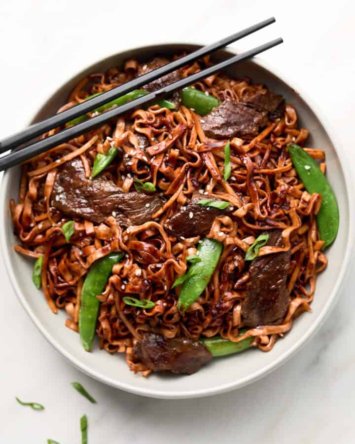 Red Thai Curry Beef Noodle stir fry in white bowl with chopsticks