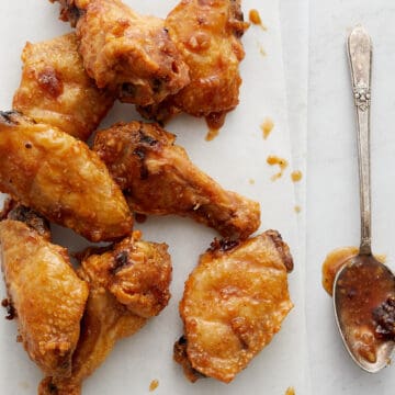 Wings on white paper and metal rack with parsley and spoon.