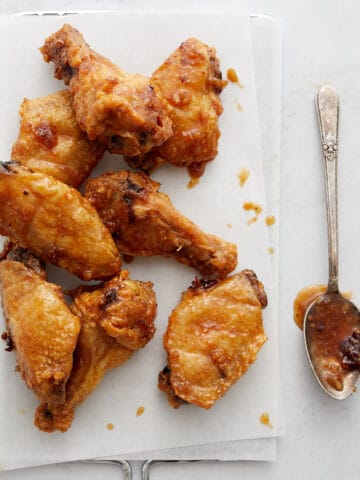 Wings on white paper and metal rack with parsley and spoon.