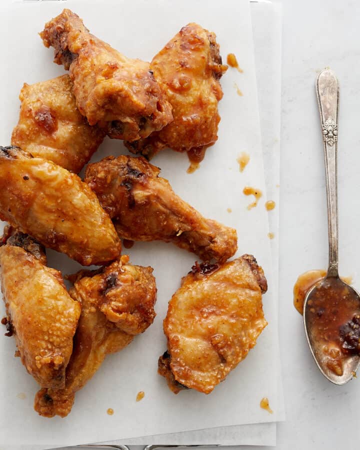 Wings on white paper and metal rack with parsley and spoon.