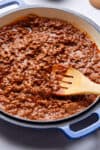 close up photo of chili in blue cast iron pan with wooden spoon