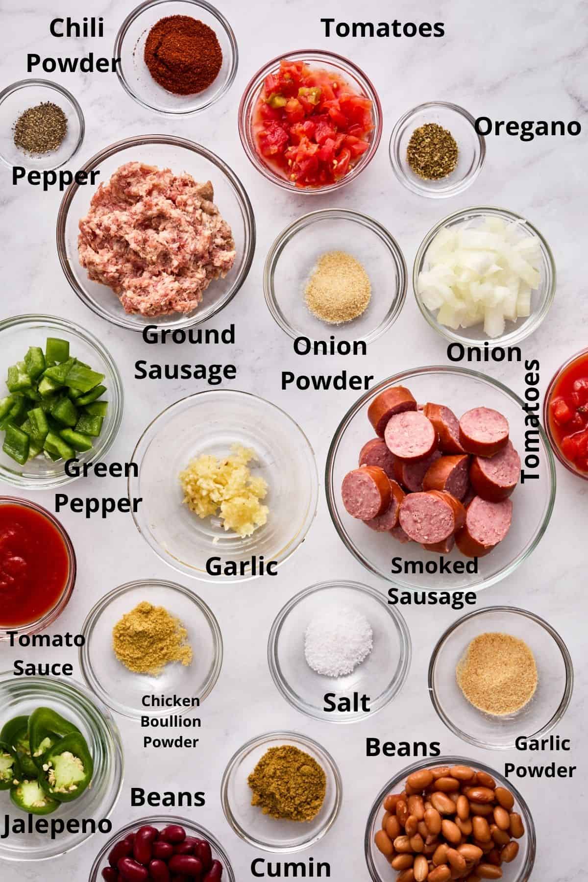 Slow cooker chili ingredients in clear bowls with each bowl labeled with each ingredient.