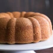 Side closeup on the Delicious Amaratto Bundt Cake with the perfect texture, presented on a cute white stand with a dark background