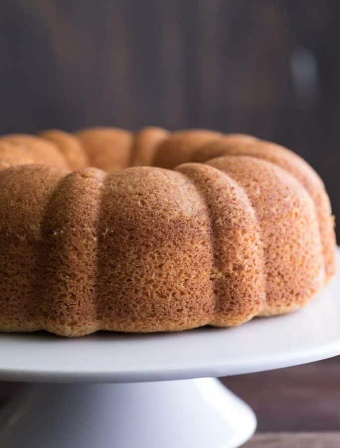 Side closeup on the Delicious Amaratto Bundt Cake with the perfect texture, presented on a cute white stand with a dark background