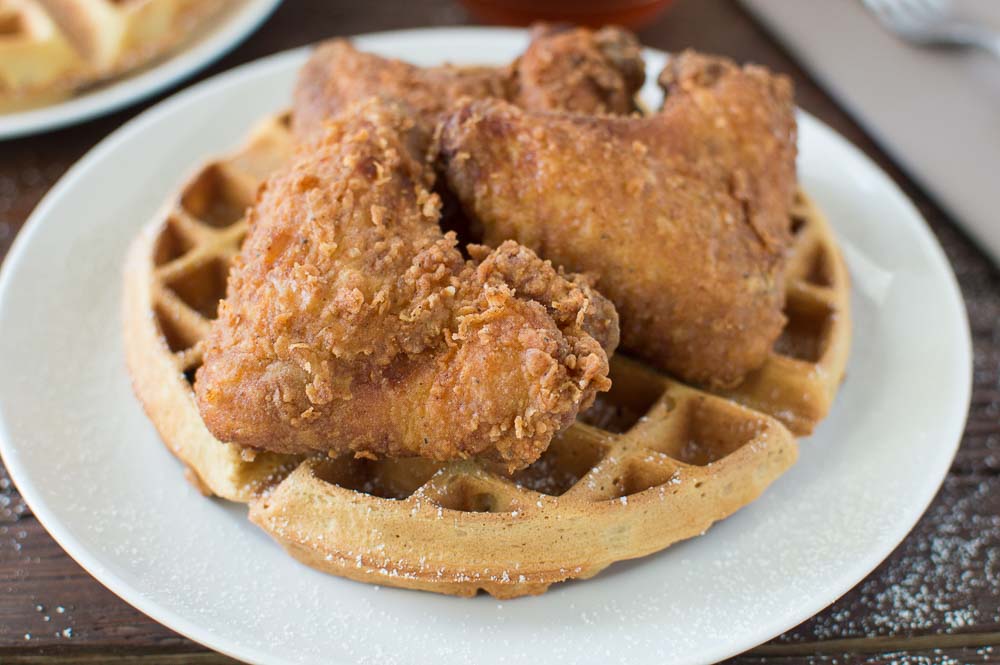 Serving Buttermilk Peach Waffles with Buttermilk Fried Chicken to the table made of wood