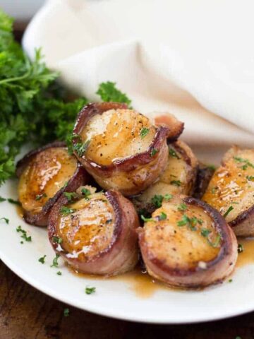 Bacon Wrapped Scallops with Bourbon Peach Glaze served on a white plate