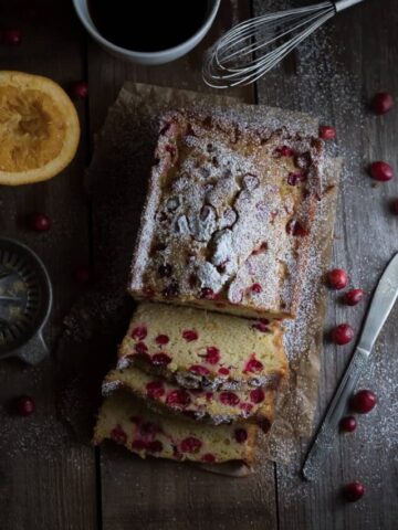 Overhead on the delicious Homemade Cranberry Orange Bread with lots of cranberries around on the table