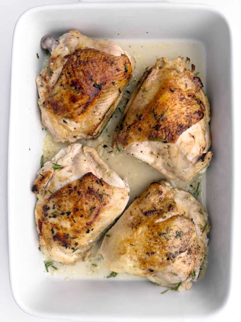 Chicken in marinade in glass bowl.