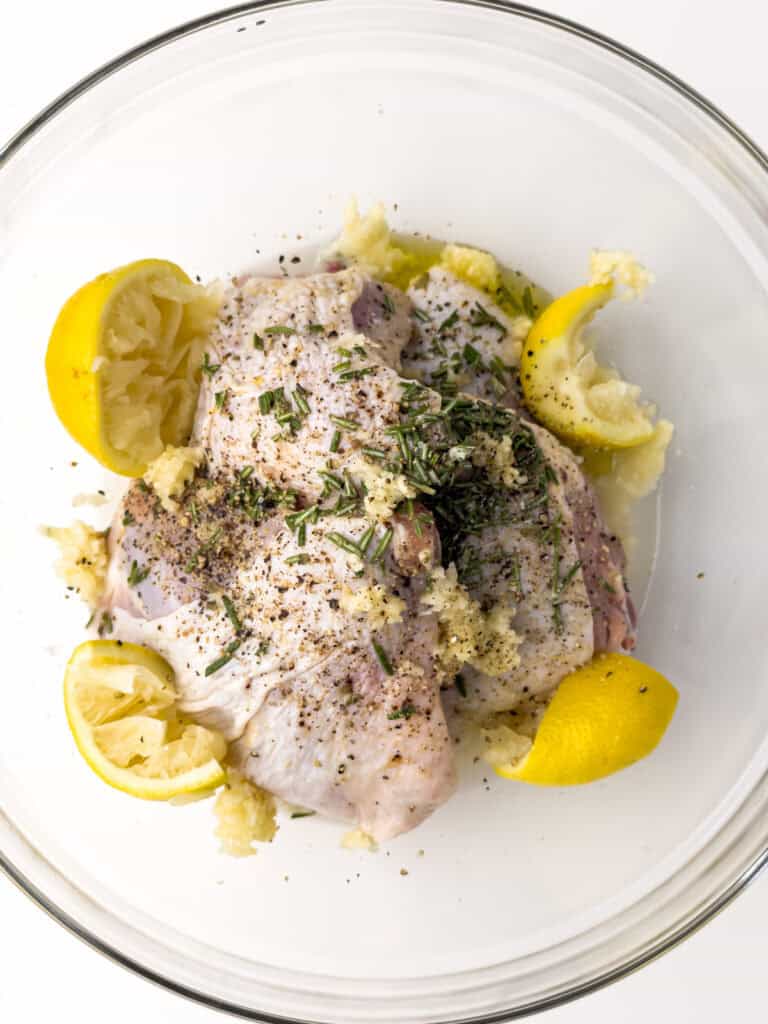 Chicken in marinade in glass bowl.
