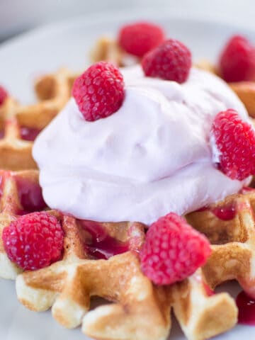 Buttermilk Waffles with Raspberry Champagne Mascarpone Cream served on a white plate in the morning