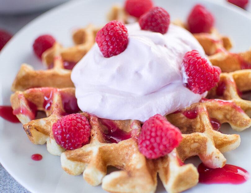 Buttermilk Waffles with Raspberry Champagne Mascarpone Cream served on a white plate in the morning