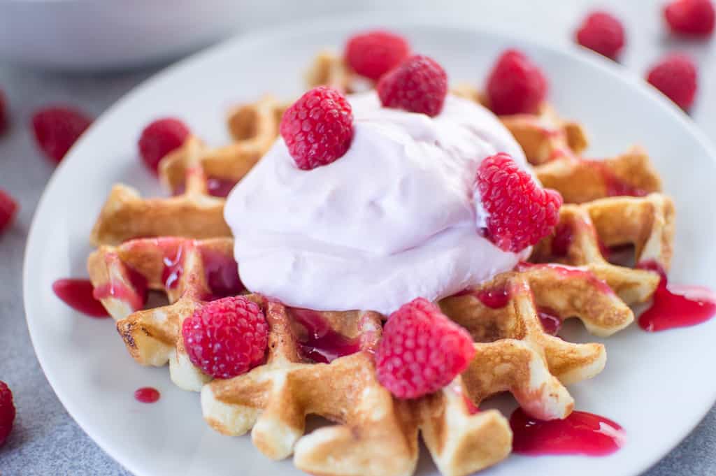 Buttermilk Waffles with Raspberry Champagne Mascarpone Cream served on a white plate in the morning