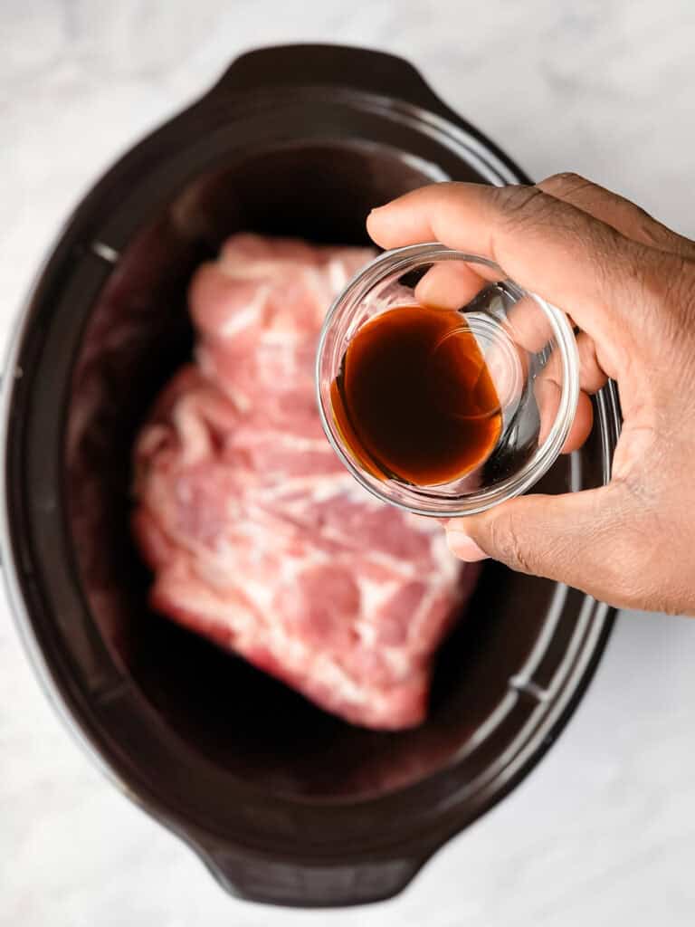 pouring liquid smoke on pork in slow cooker