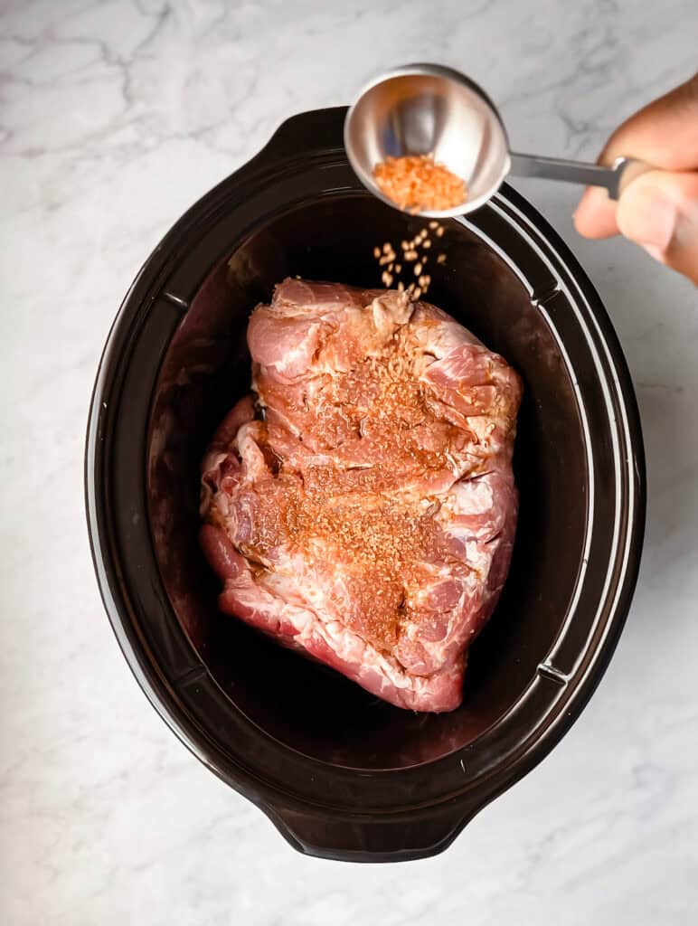 pouring salt on pork in slow cooker