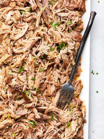cooked kalua pork on white plate with fork