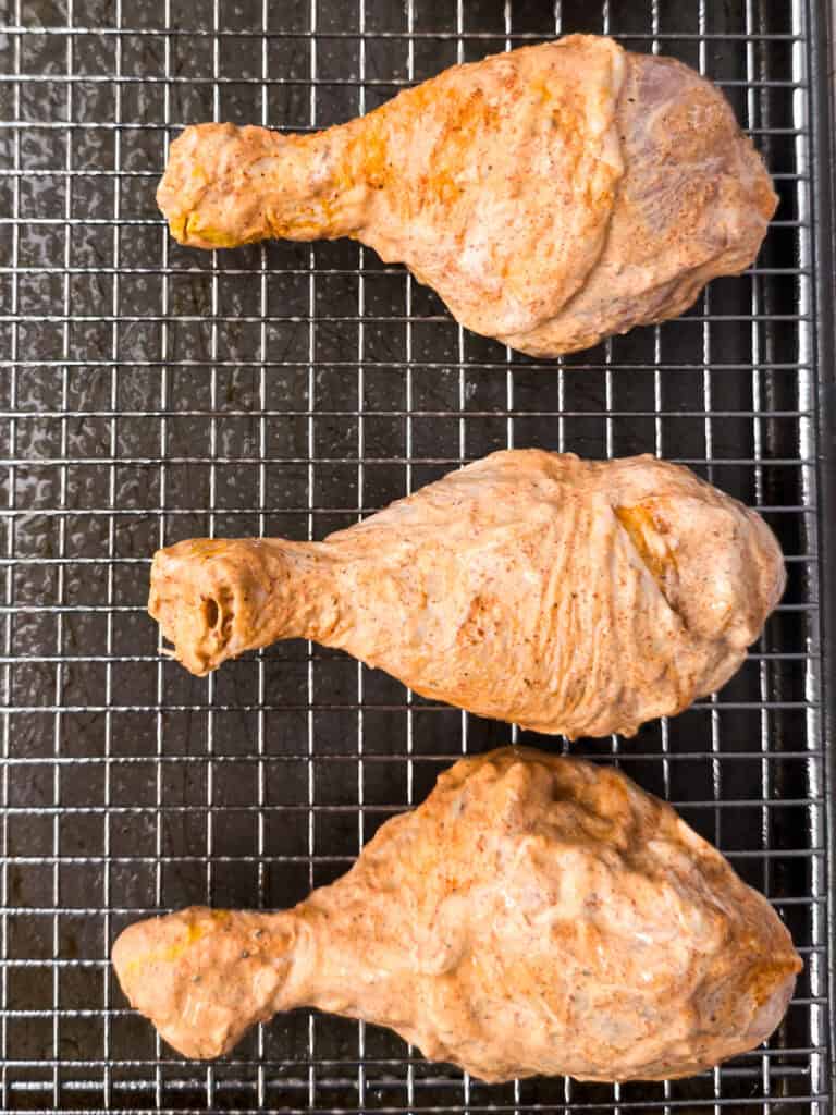 Marinated chicken legs on pan with rack. 