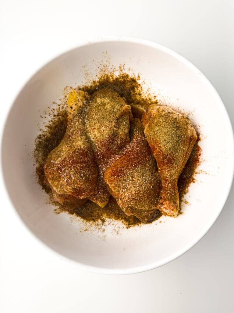 Chicken legs in spice rub in white bowl