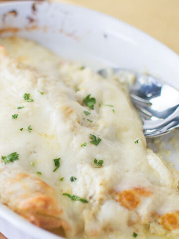 white sauce enchiladas in white dish with spoon