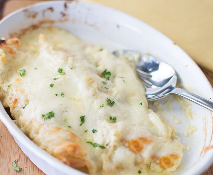 white sauce enchiladas in white dish with spoon 