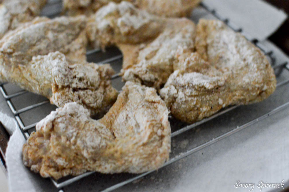 Letting the chicken rest on a baking rack after flouring the chicken