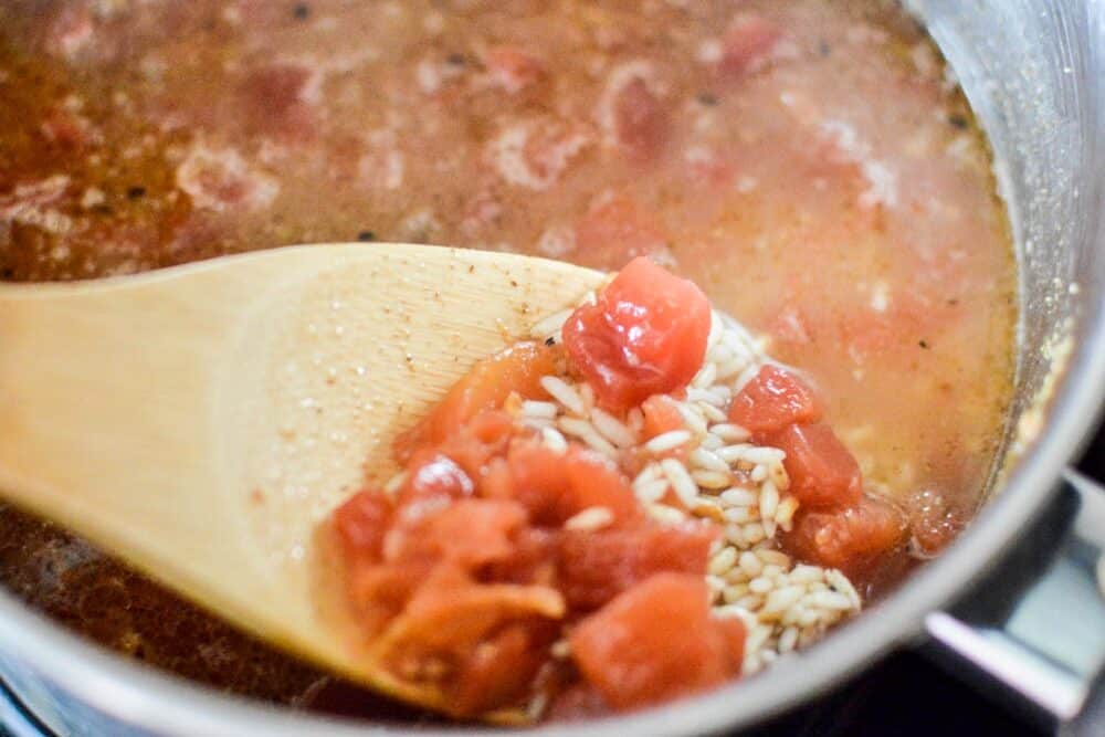 Rice cooking in pot with spoon stirring ingredients