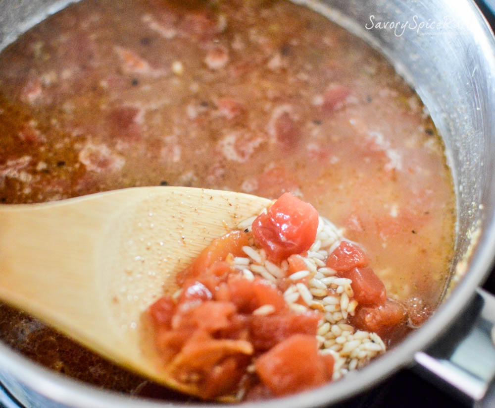 Closeup on the delicious rice and other ingredients on a wooden ladle above the pan