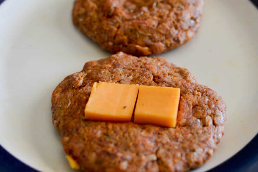 Placing a slice of the cheddar cheese onto the hamburger patties