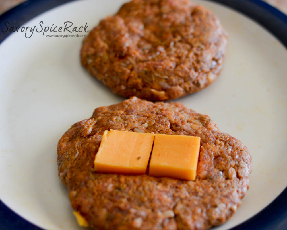 Placing a slice of the cheddar cheese onto three of the hamburger patties