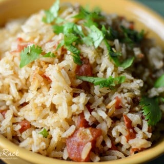 Mexican Rice served in a yellow bowl with bacon and decorated with green herbs