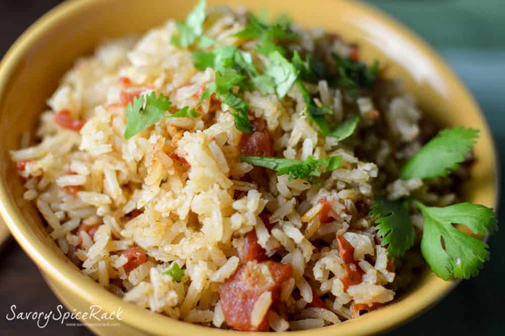 Mexican Rice served in a yellow bowl with bacon and decorated with green herbs